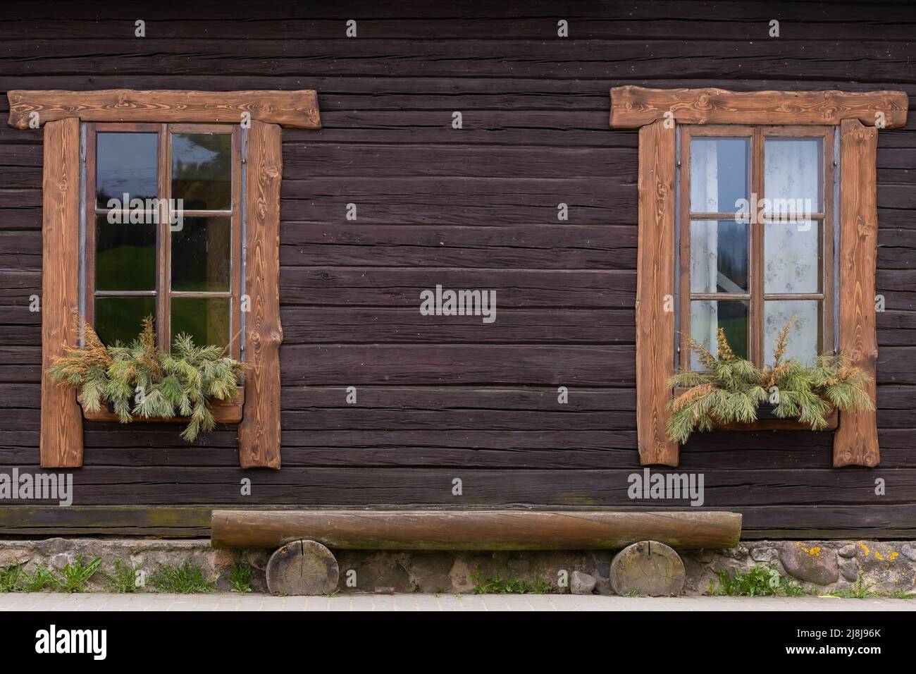 The facade of an old wooden house with two windows and a bench Stock ...