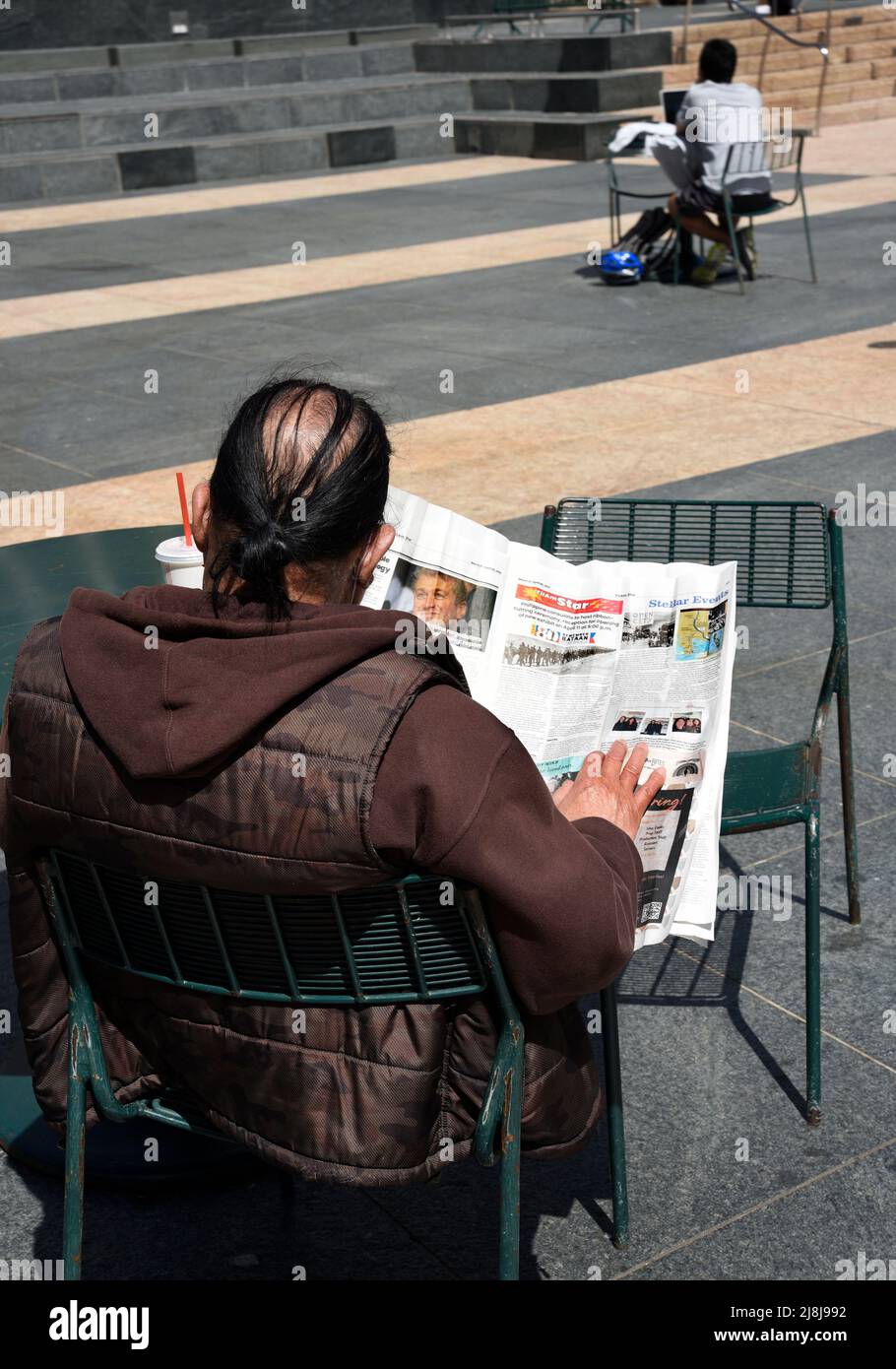 A man reads a newspaper as he relaxes in Union Square in San Francisco, California. Stock Photo