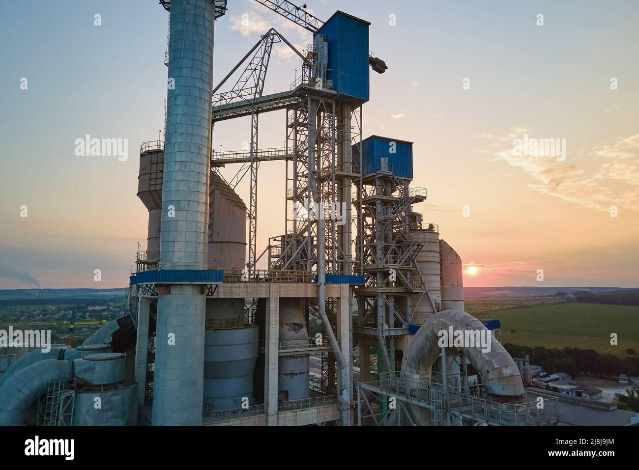 Cement plant with high factory structure and tower cranes at industrial production area. Manufacture, global industry and air pollution concept Stock Photo
