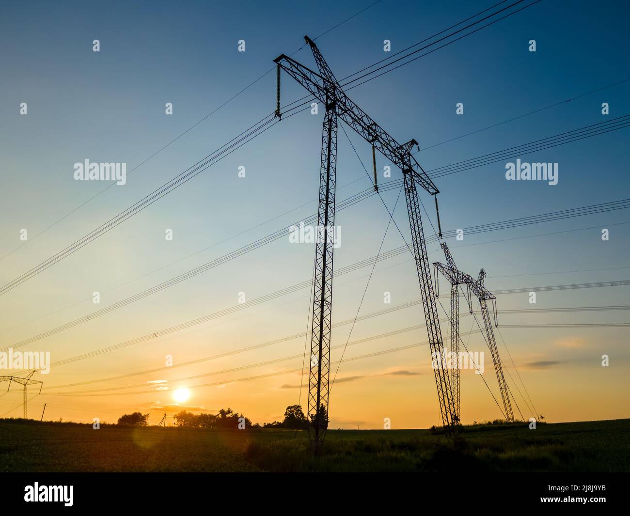 Dark silhouette of high voltage towers with electric power lines at ...