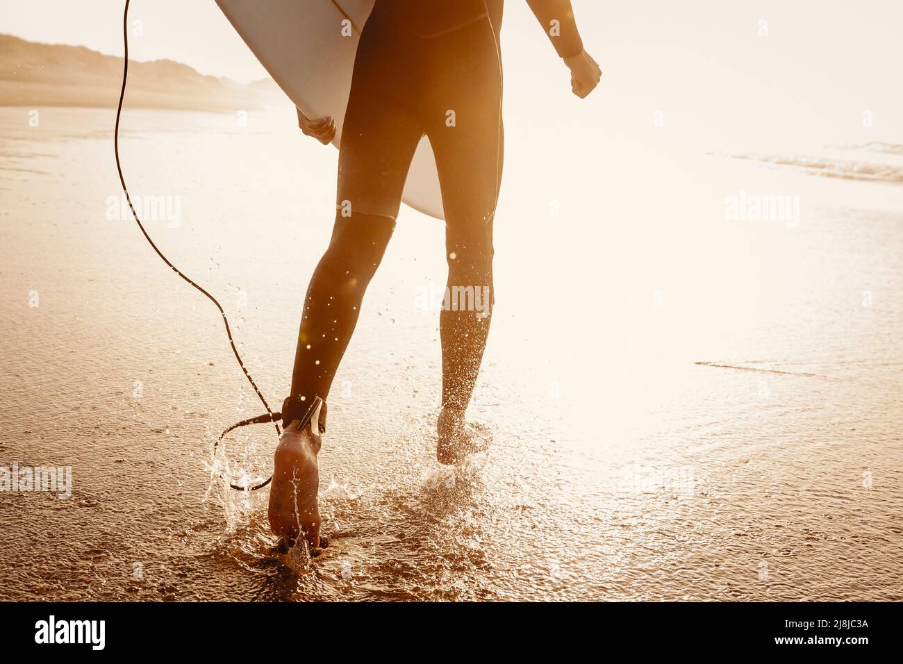 A surfer with his surfboard running to the waves Stock Photo