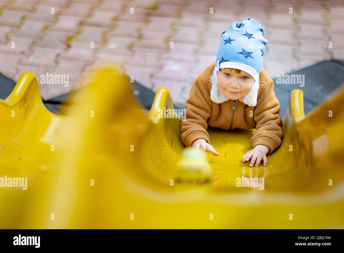 Cheerful funny little boy in a blue hat and warm clothes plays on the