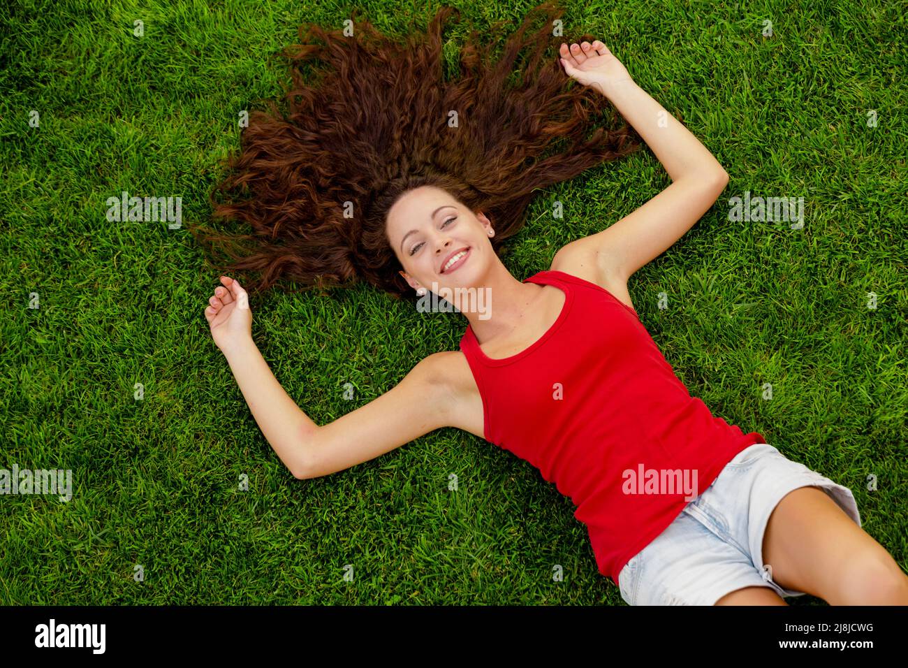 Outdoor portrait of a beautiful young woman lying on the grass Stock Photo