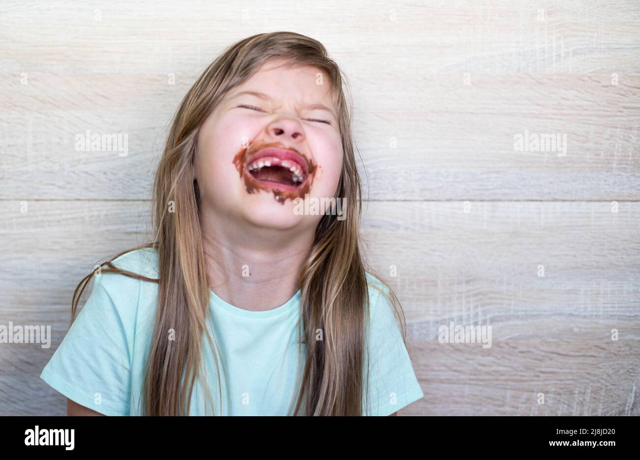 Laughing little girl eating chocolate dirty face Stock Photo