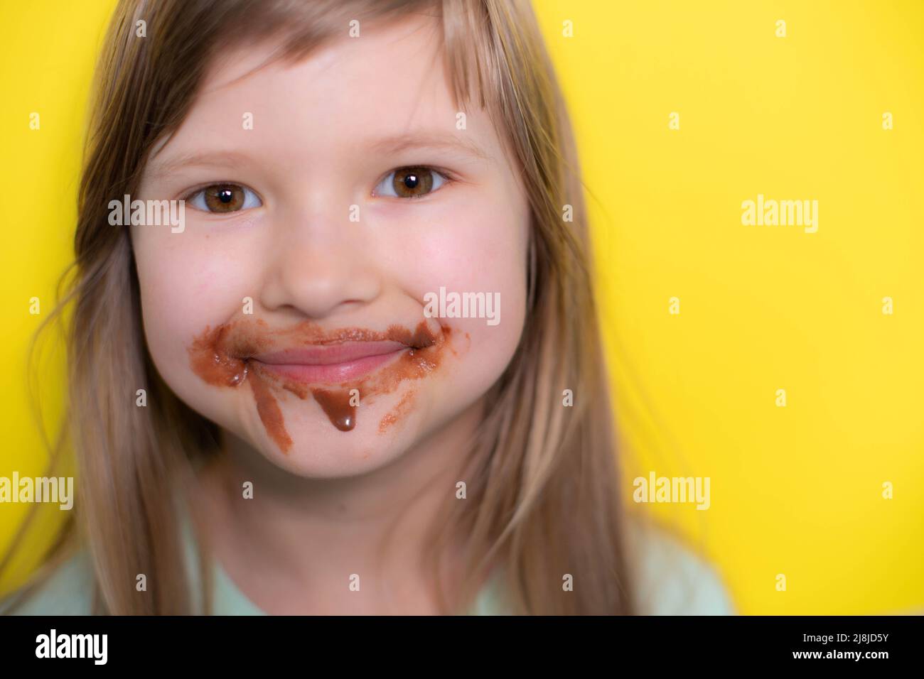 Happy little girl eating chocolate dirty face Stock Photo