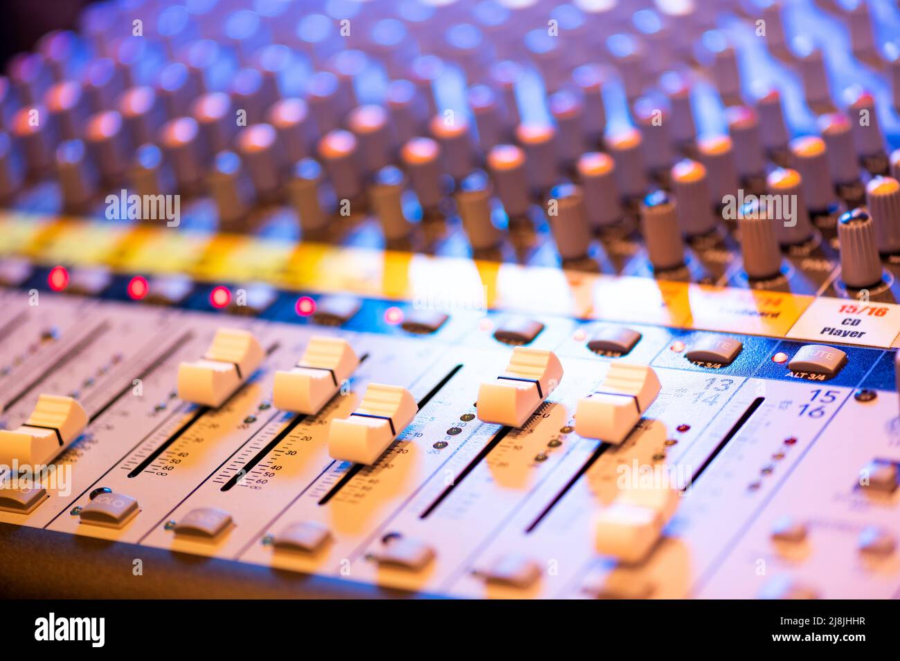 Close up detail of a professional music mixing deck showing the slider controls in ambient night light Stock Photo
