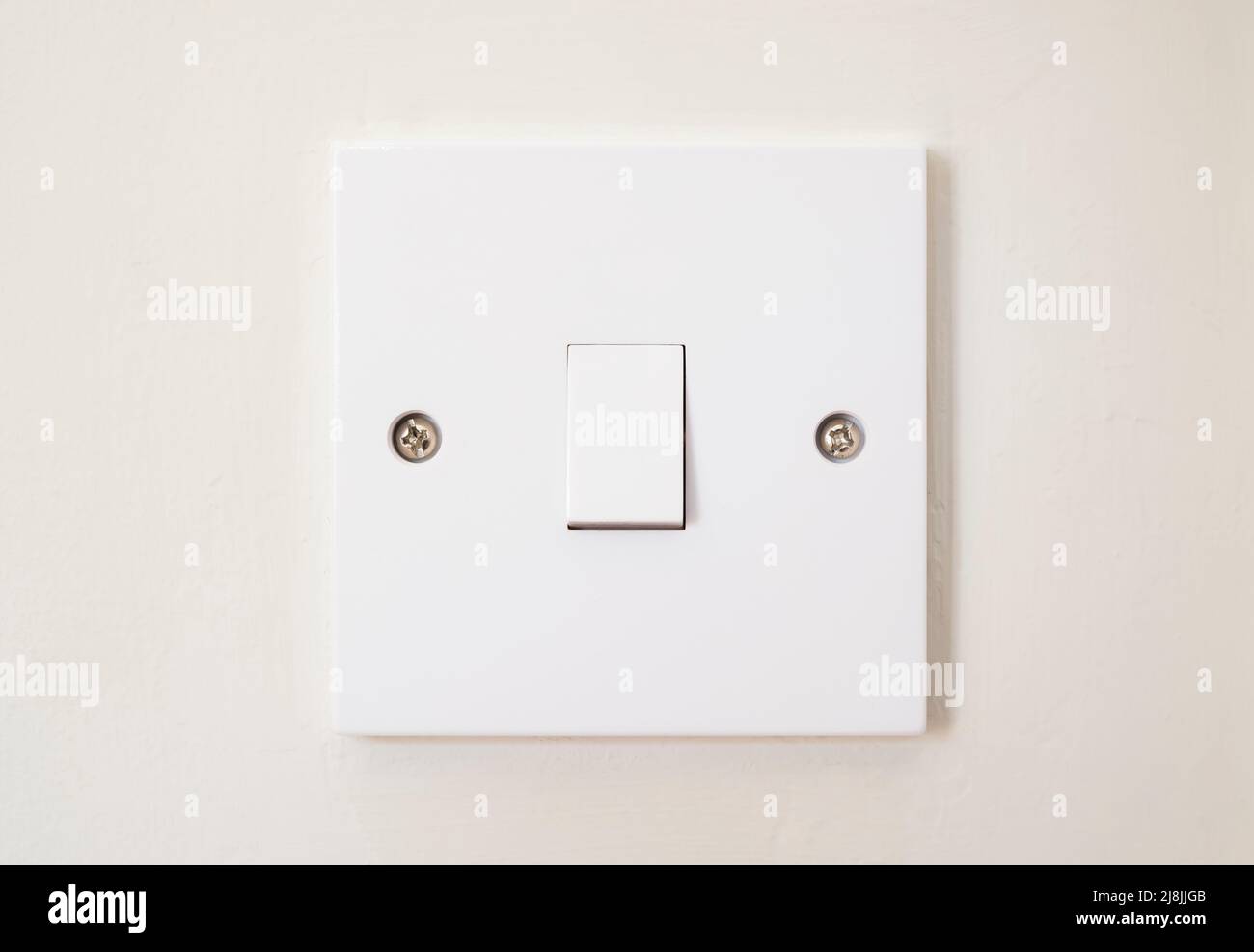 White plastic room light switch on a wall, home interior lighting, UK Stock Photo