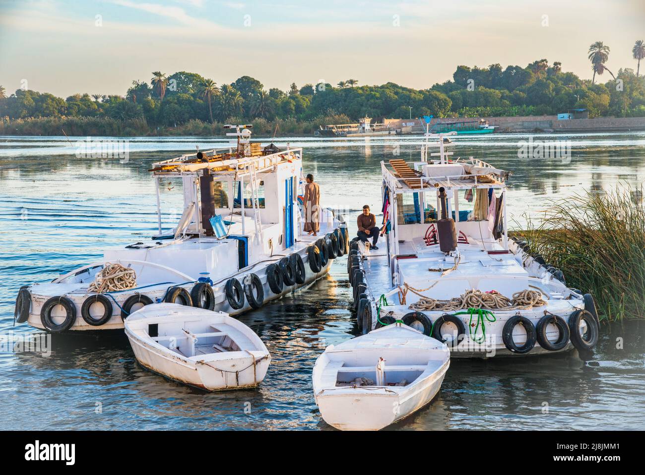 two tug boats and two felucca boats without sails on the Nile River Stock Photo