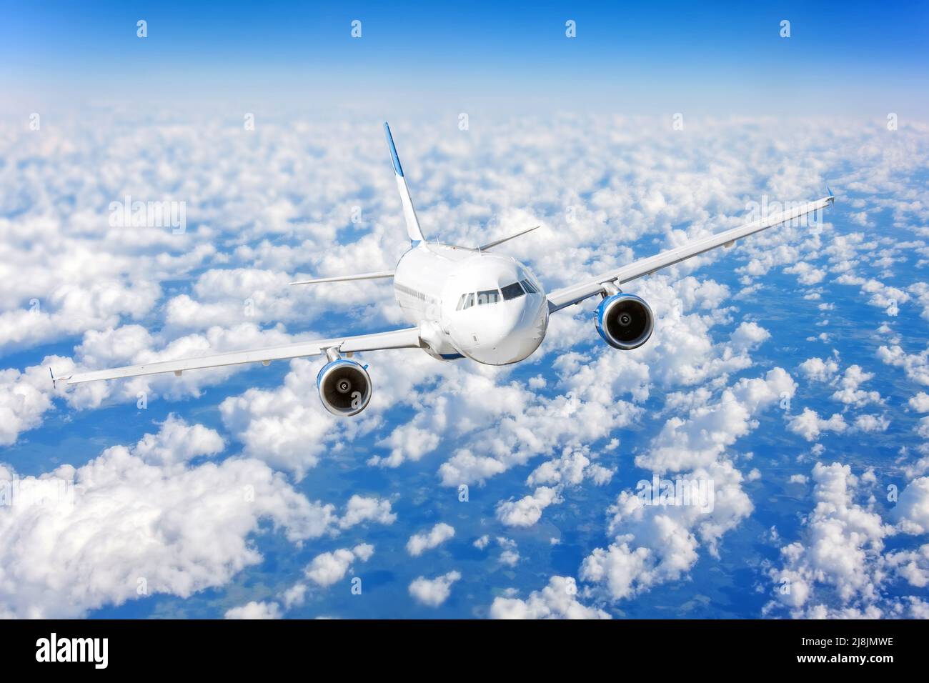 Commercial airplane flying over bright blue sky and white clouds Stock ...
