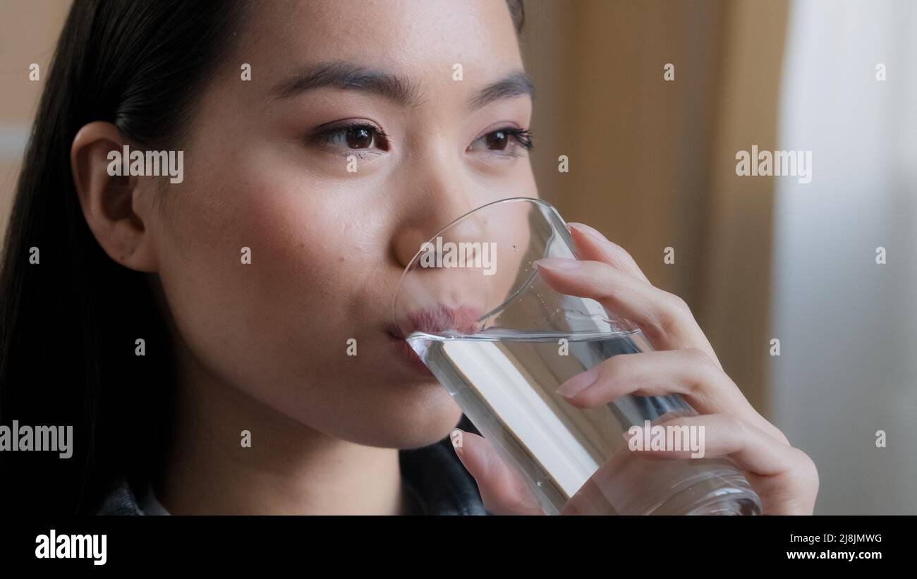 Close up asian woman drinking clean water home delivery holding glass lunch morning daily ritual good habit girl feels thirsty health care hydration Stock Photo