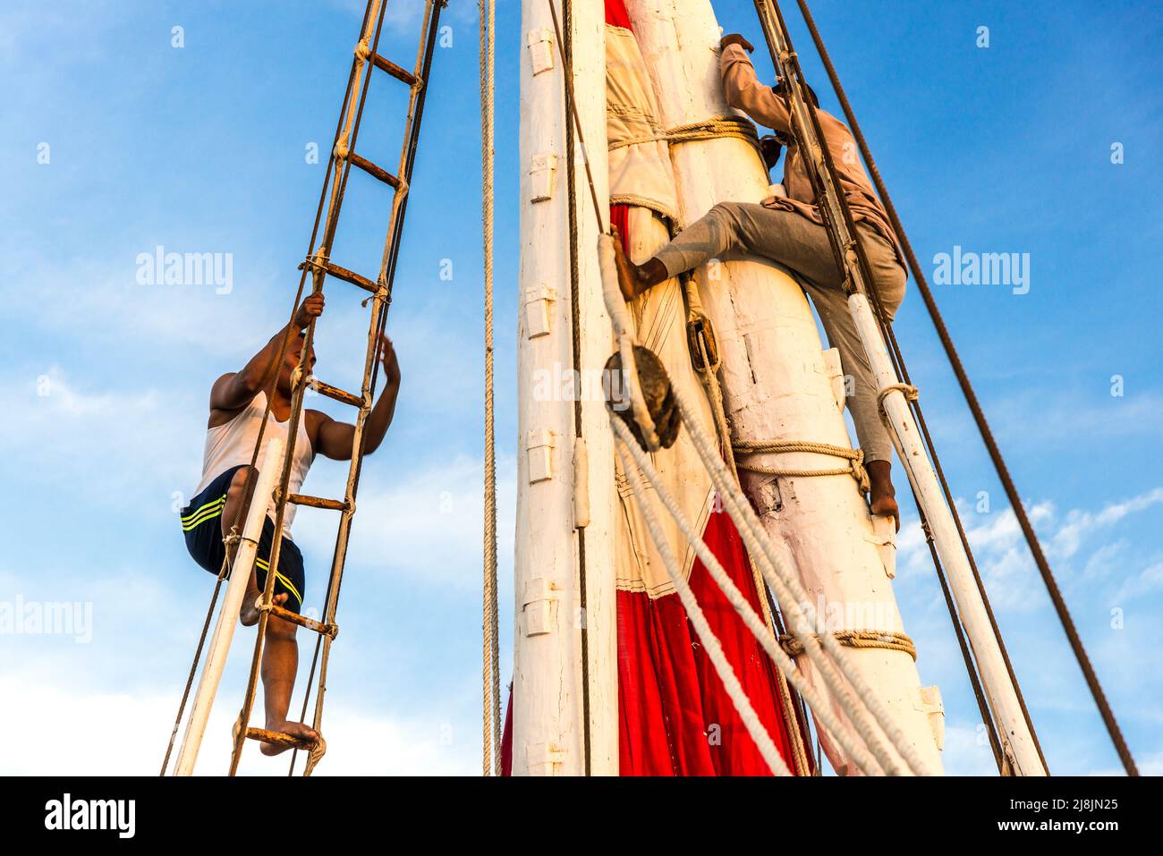 two men high on the mast fixing the rigigng and sails Stock Photo