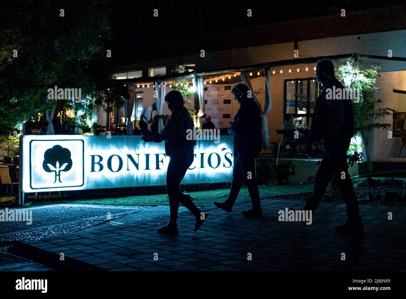 Three figures in silhouette walk past the upscale Bonifacio’s Restaurant in San Carlos, Sonora, Mexico. Stock Photo