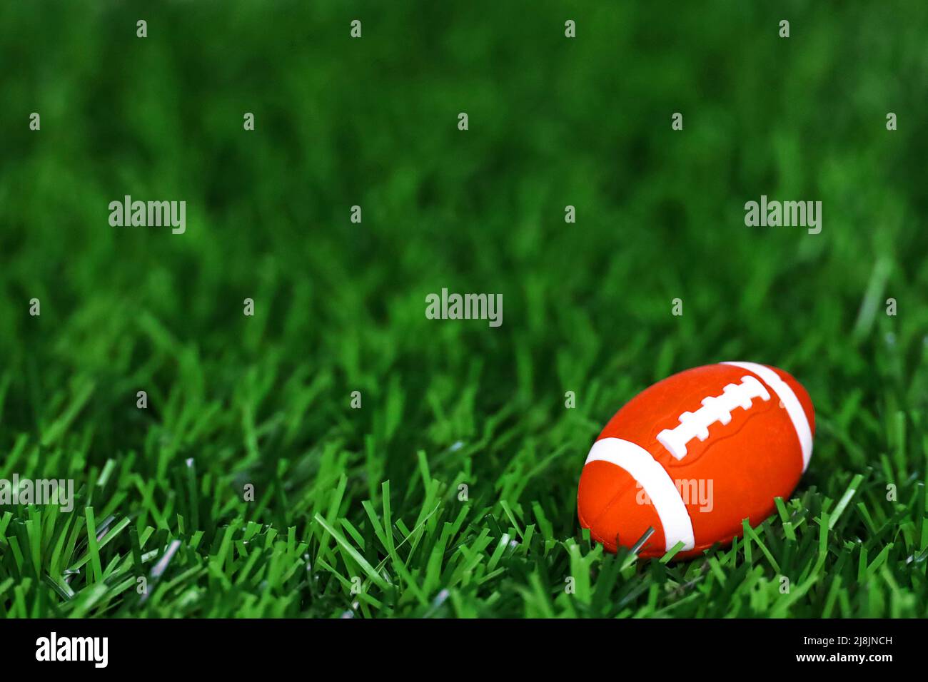Still life photo of a miniature toy American football ball placed on artificial turf Stock Photo