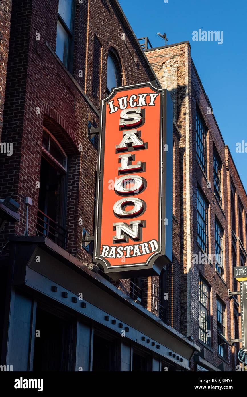 A burntorange sign for the Lucky Bastard Saloon hanging from a brick