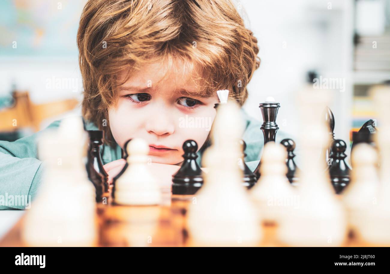 Cute little boy playing chess. Thinking kid. Concentrated boy developing chess strategy, playing board game. Stock Photo