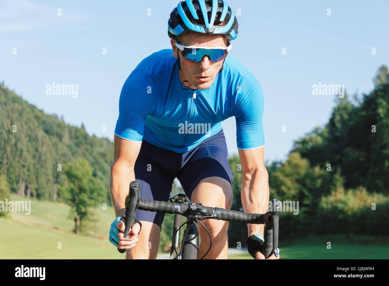 Muscular man, professional racing bicyclist sprint cycling, with posterior raised out of the saddle and pedaling hard Stock Photo