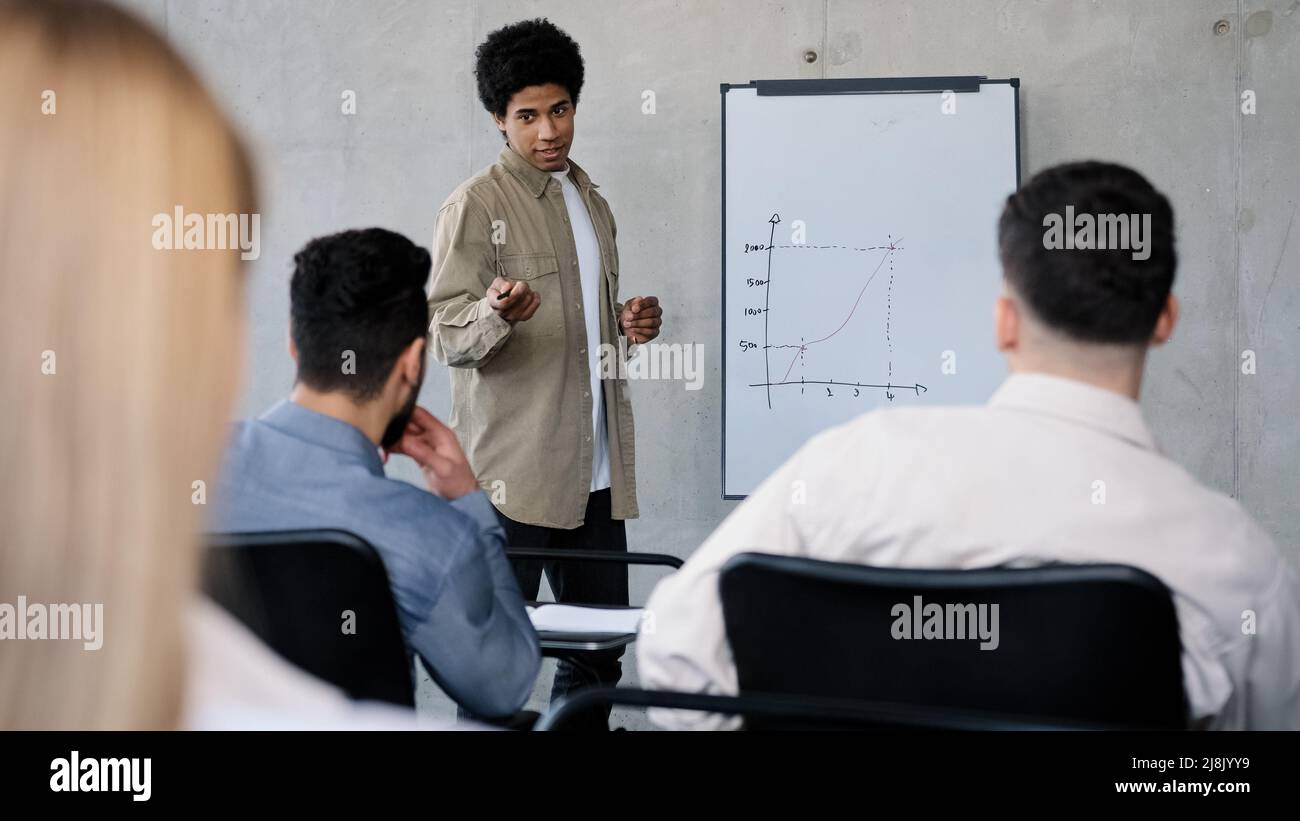 Young male manager presenting project plan to colleagues in meeting explaining report schedule ideas on white board in office making presentation Stock Photo