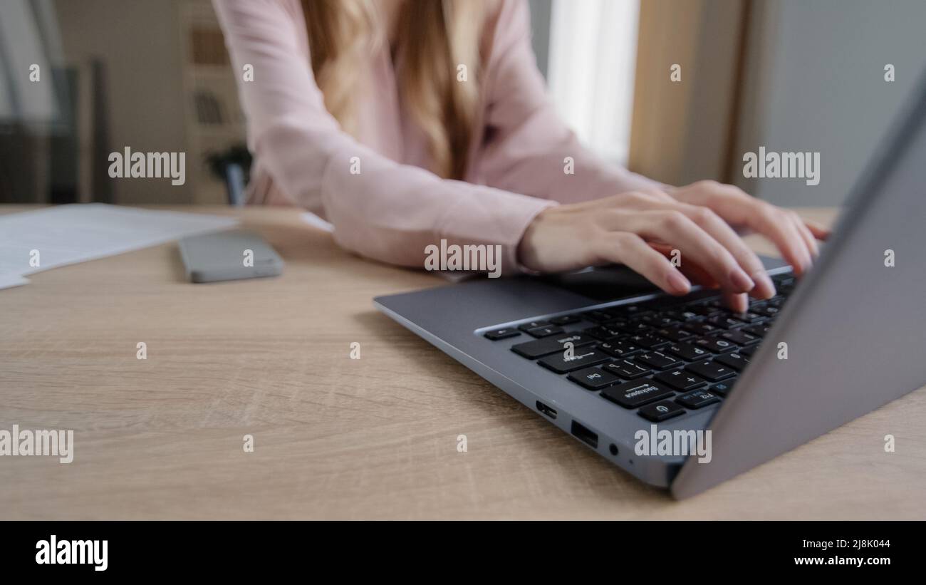 Close-up female hands with papers sorting documents typing on laptop at table in office. Unrecognizable caucasian business woman teacher paperwork at Stock Photo