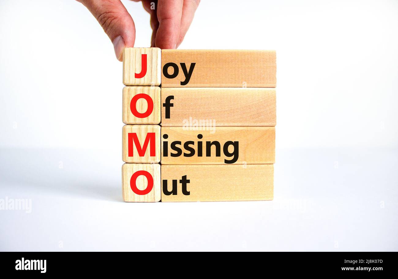 JOMO joy of missing out symbol. Concept words JOMO joy of missing out on wooden blocks on a beautiful white background. Businessman hand. Business JOM Stock Photo