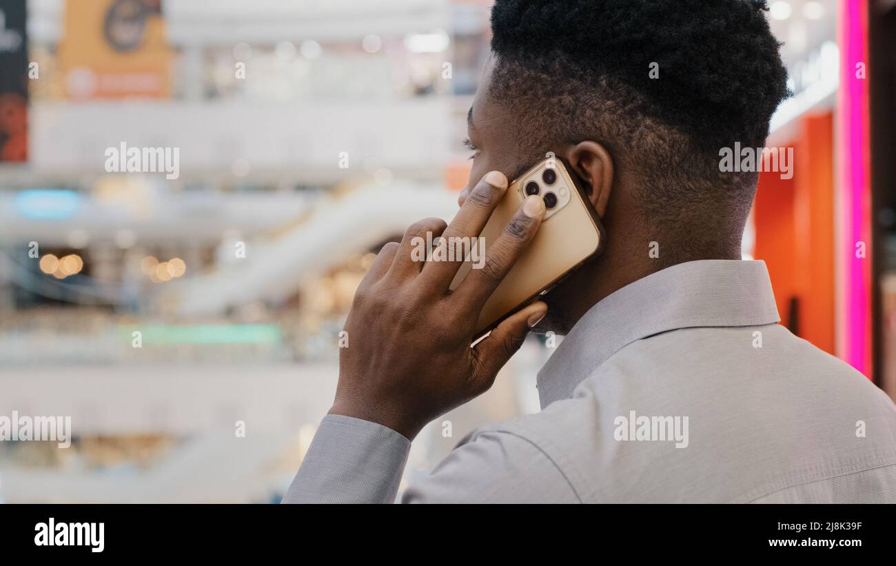 Close-up view from back young african american businessman talking on mobile phone answering business call male manager advising client speaking Stock Photo