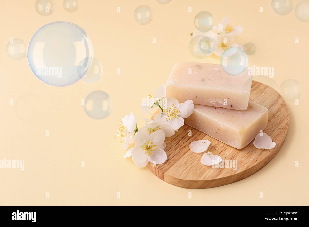 Board with soap bars and flowers on light color background Stock Photo