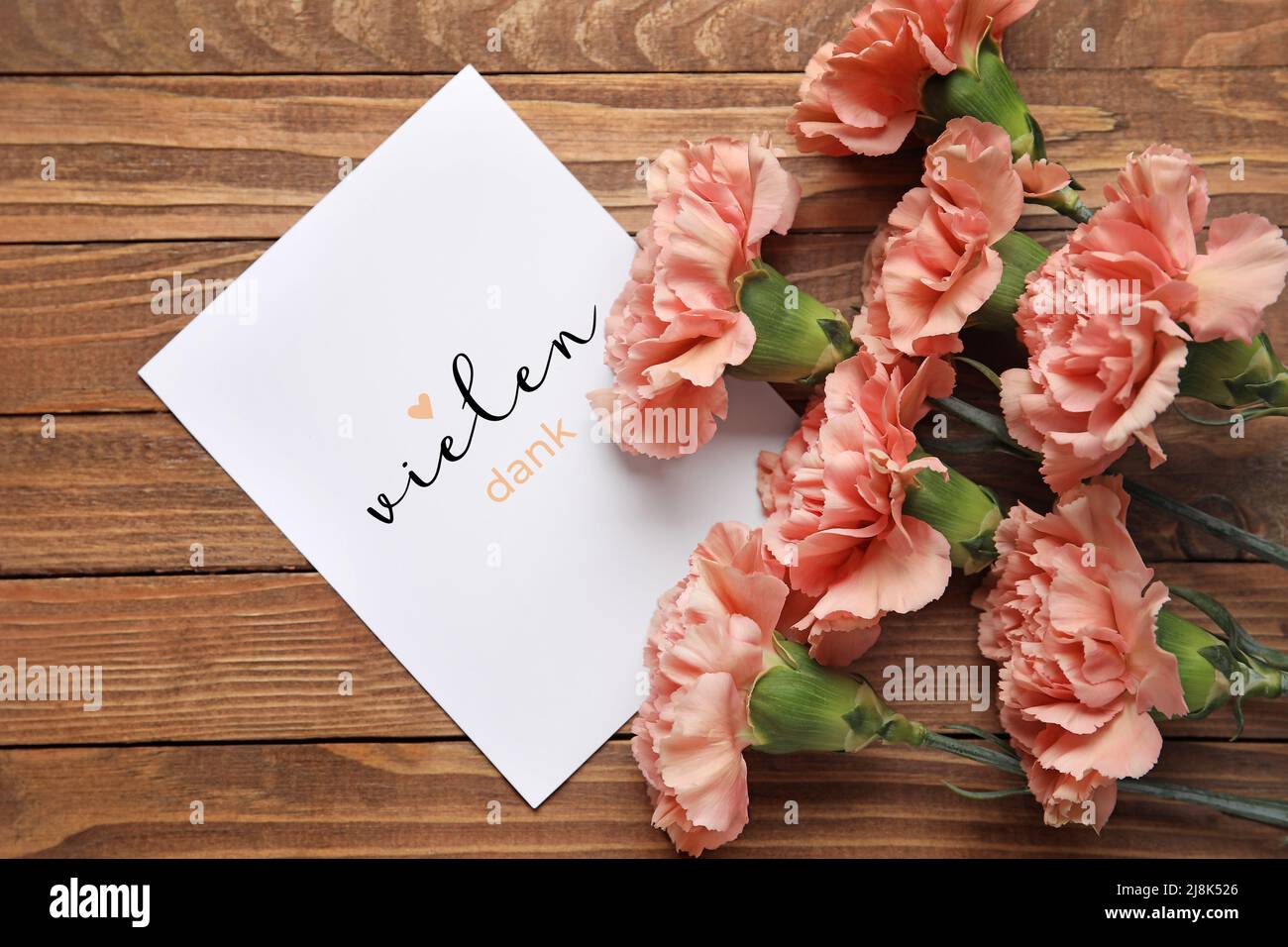 Bouquet of carnations and card with text VIELEN DANK (German for Thanks a lot) on wooden background Stock Photo