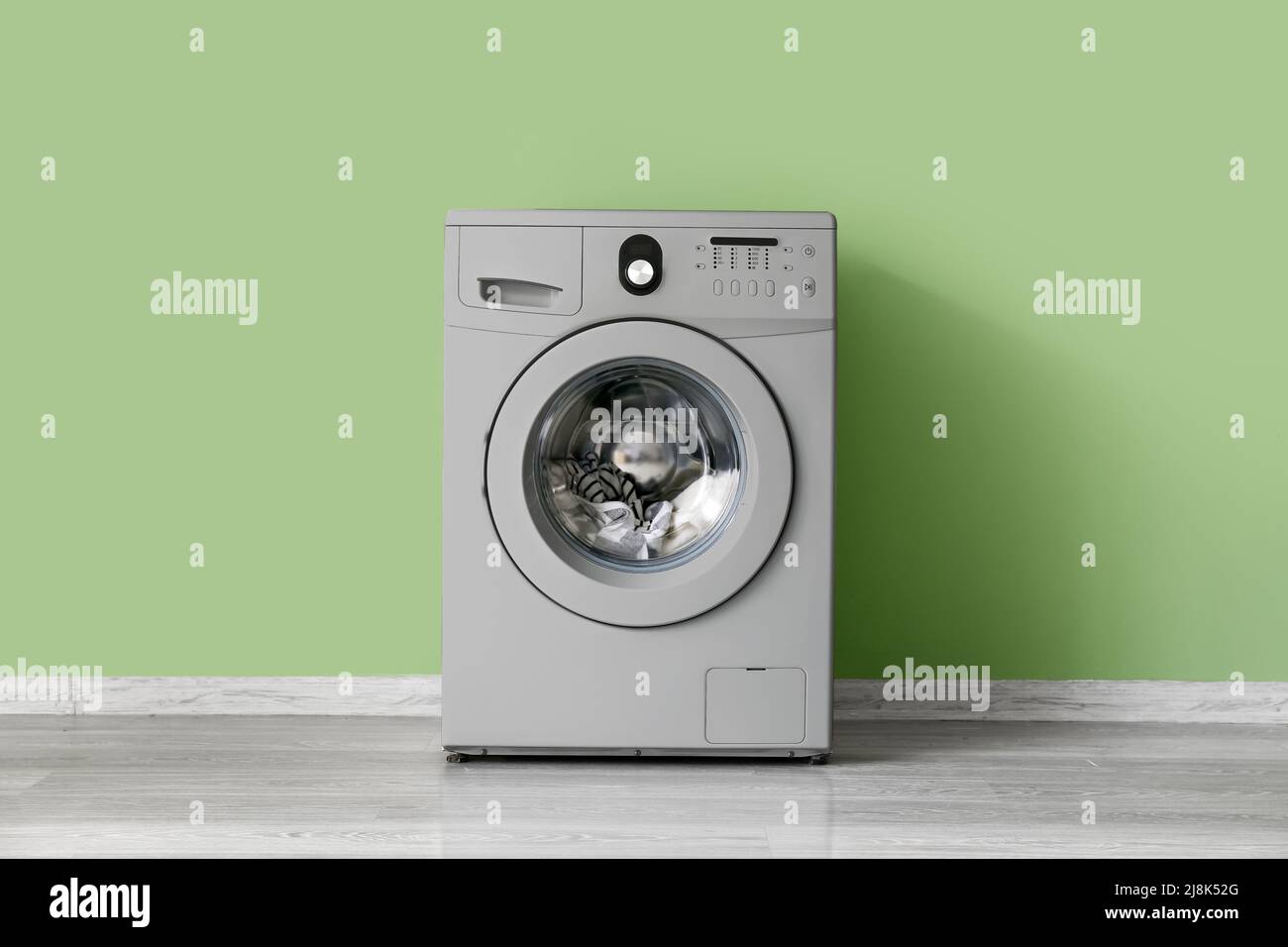 Modern washing machine near green wall Stock Photo Alamy