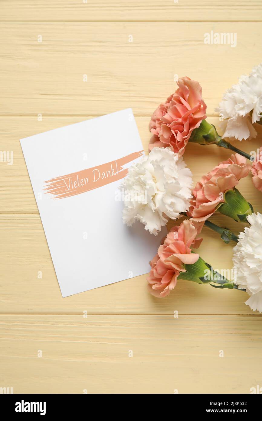 Card with text VIELEN DANK (German for Thanks a lot) and carnation flowers on color wooden background Stock Photo