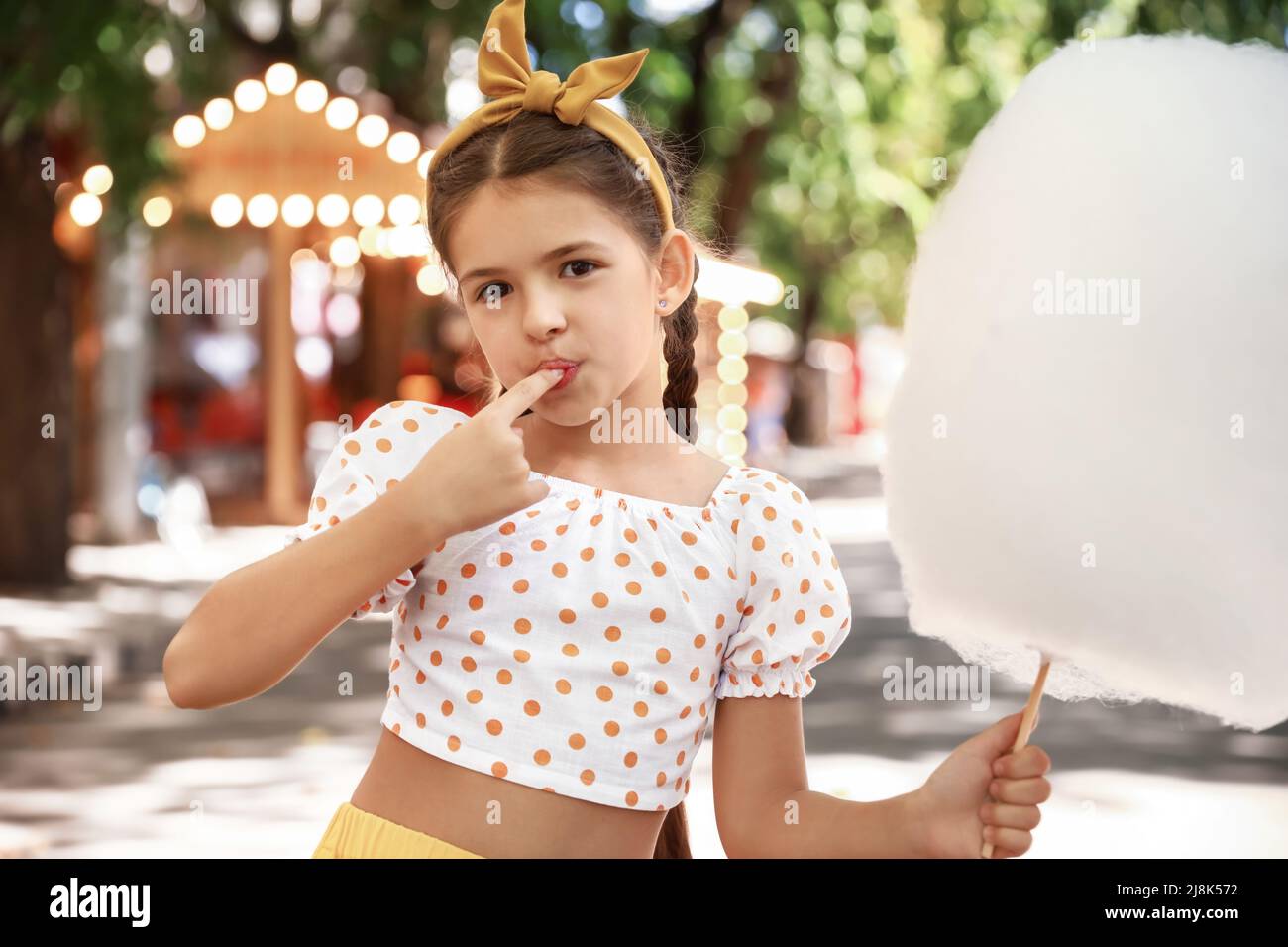 Cute little girl eating cotton candy outdoors Stock Photo Alamy