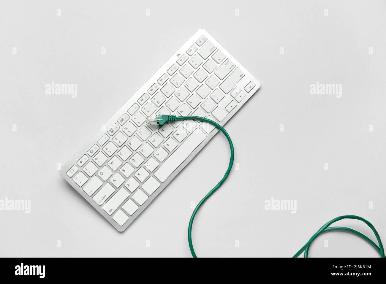 Modern keyboard and internet cable on light background Stock Photo