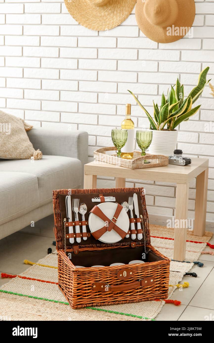 Wicker basket with dishware for picnic on carpet in living room Stock ...