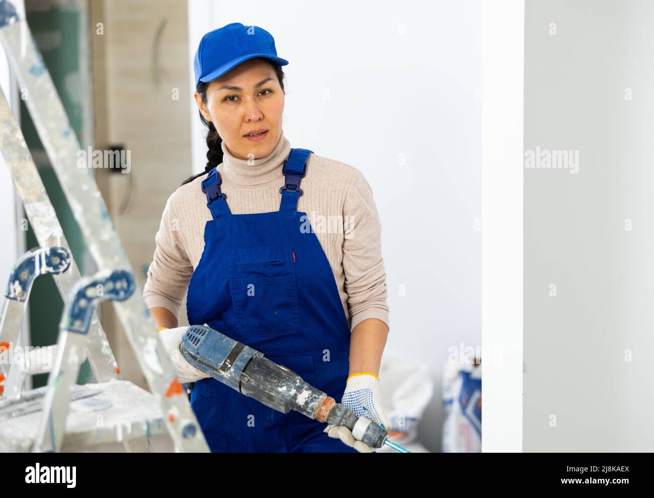 Female repairer with drill working in apartment Stock Photo - Alamy