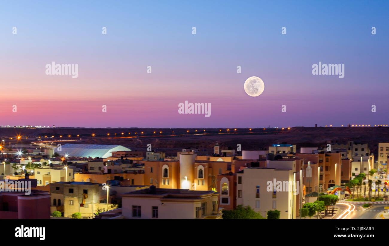 Full moon above a purple sky in Laayoune city in Morocco Stock Photo