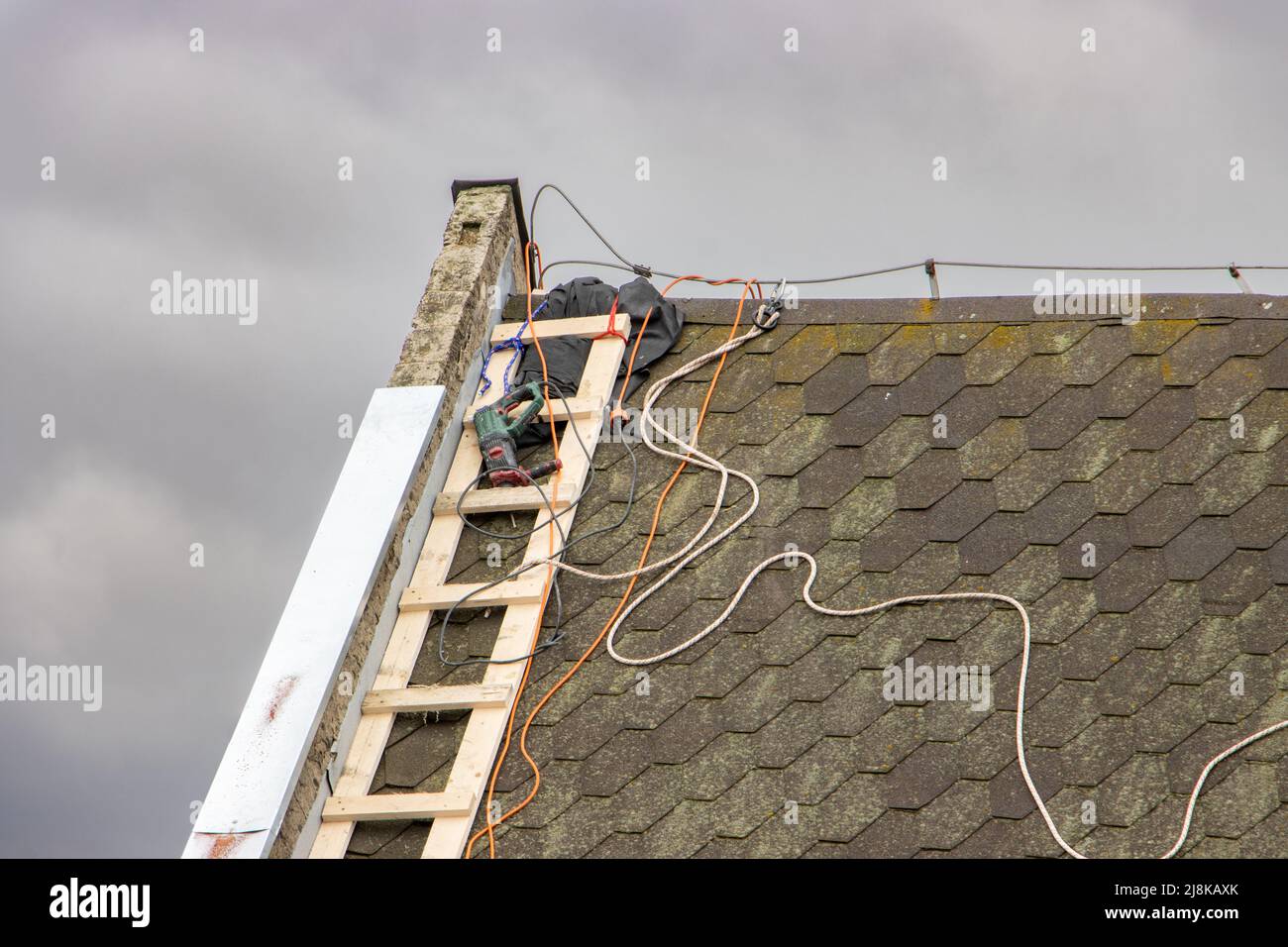 Repairman's equipment lies with a ladder on the roof of the house Stock Photo