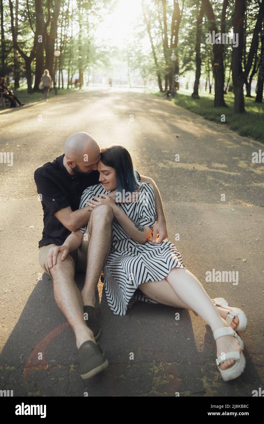 lovers sit in a hug on the asphalt against the background of the sun ...