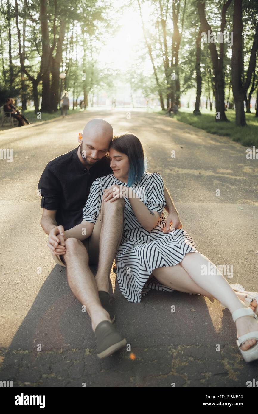 lovers sit in a hug on the asphalt against the background of the sun ...
