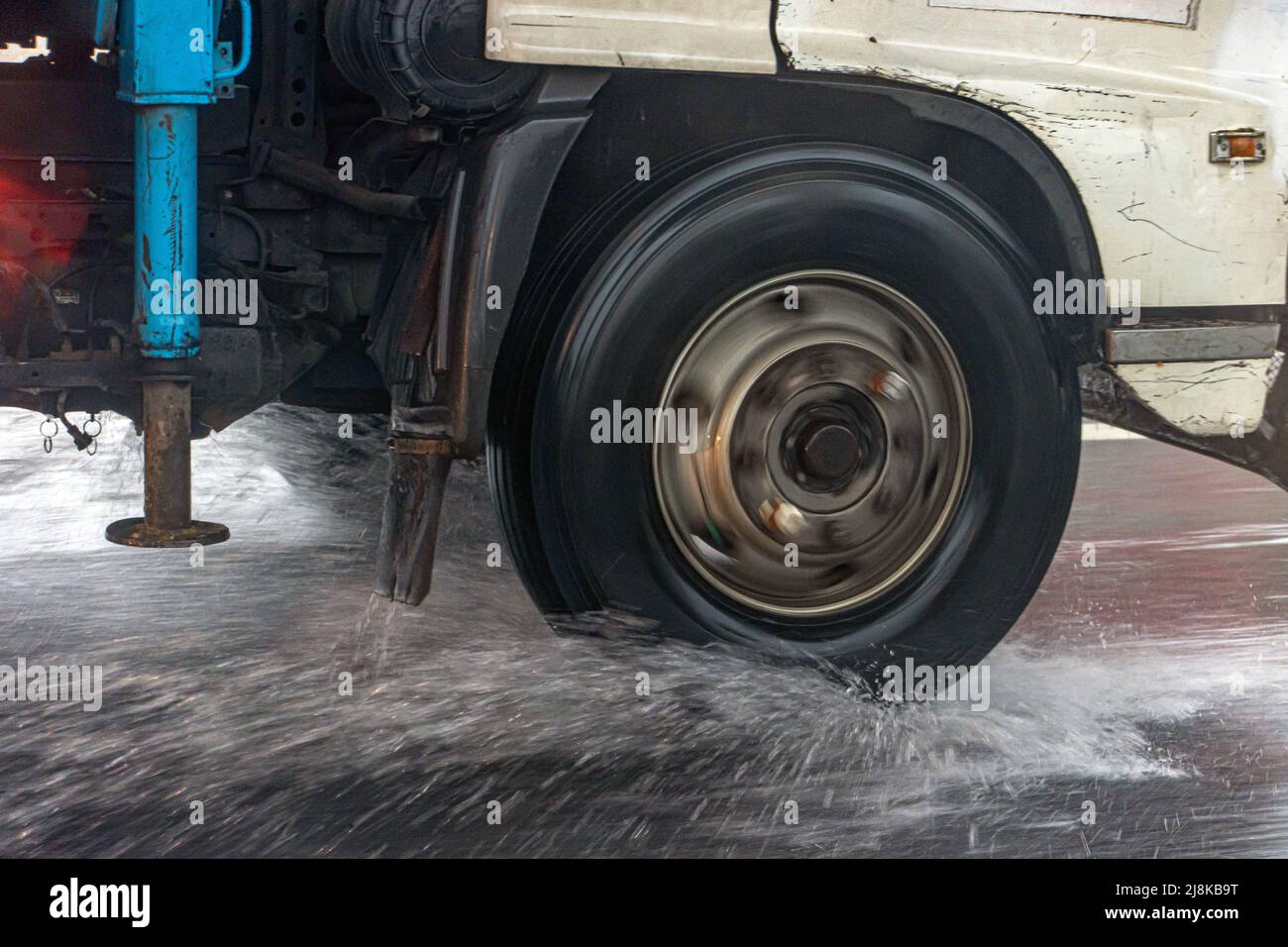Detail of the wheel of a truck driving in the puddle on a wet road. Stock Photo