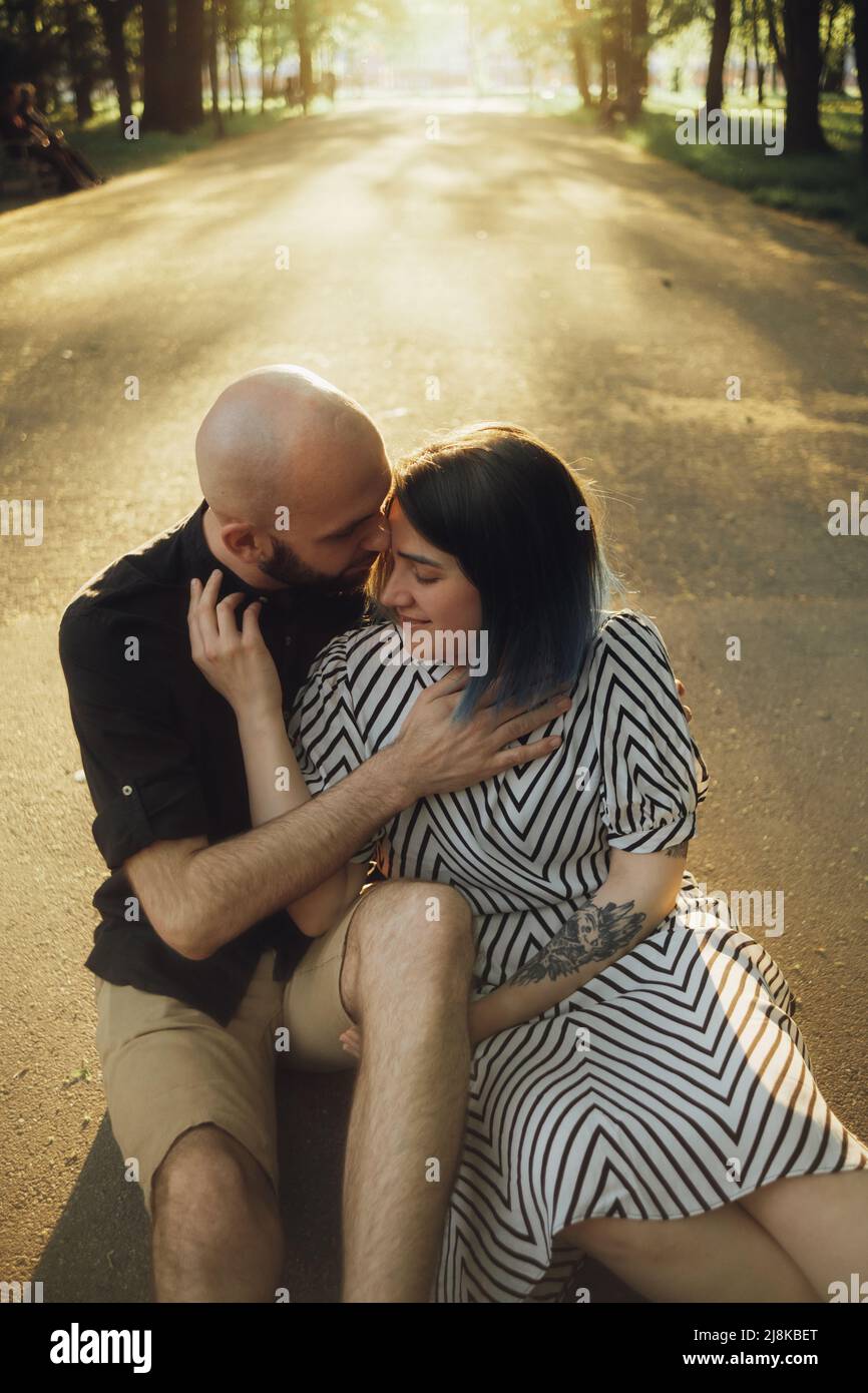 lovers sit in a hug on the asphalt against the background of the sun ...