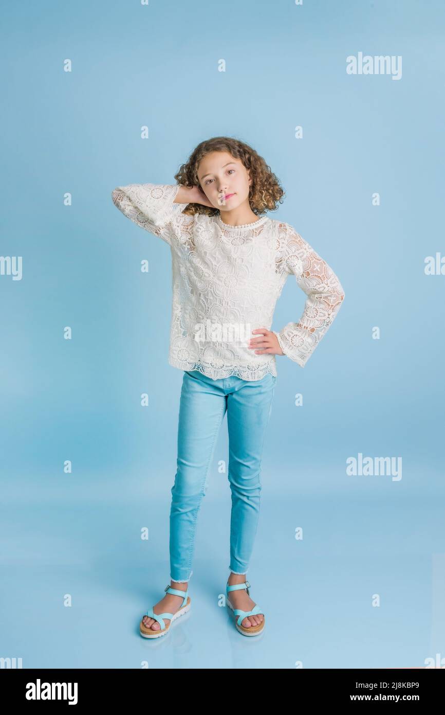 Studio portrait of young girl in candid standing pose with hand behind head Stock Photo