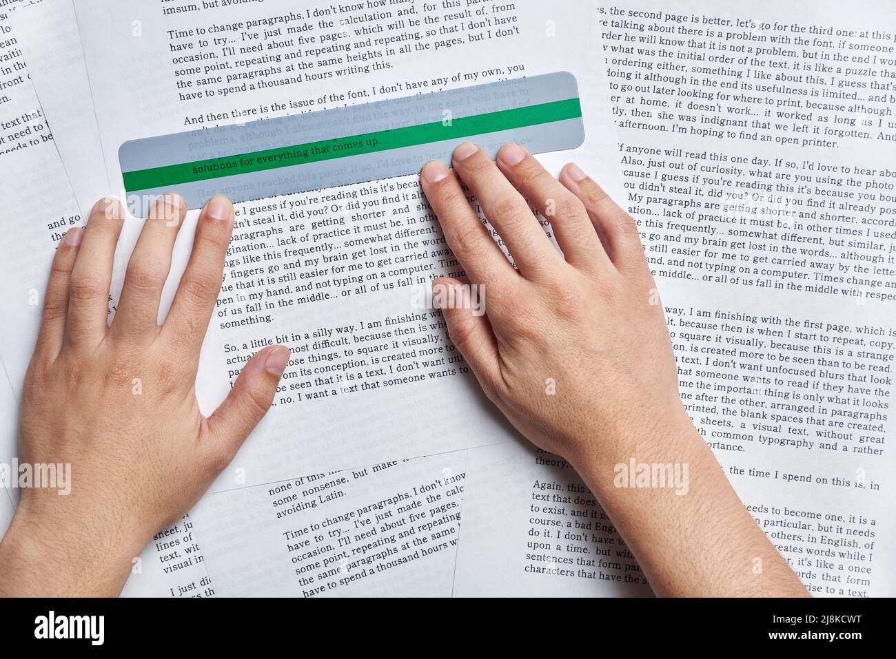 Unrecognizable young person reading with the help of a coloured ruler ...