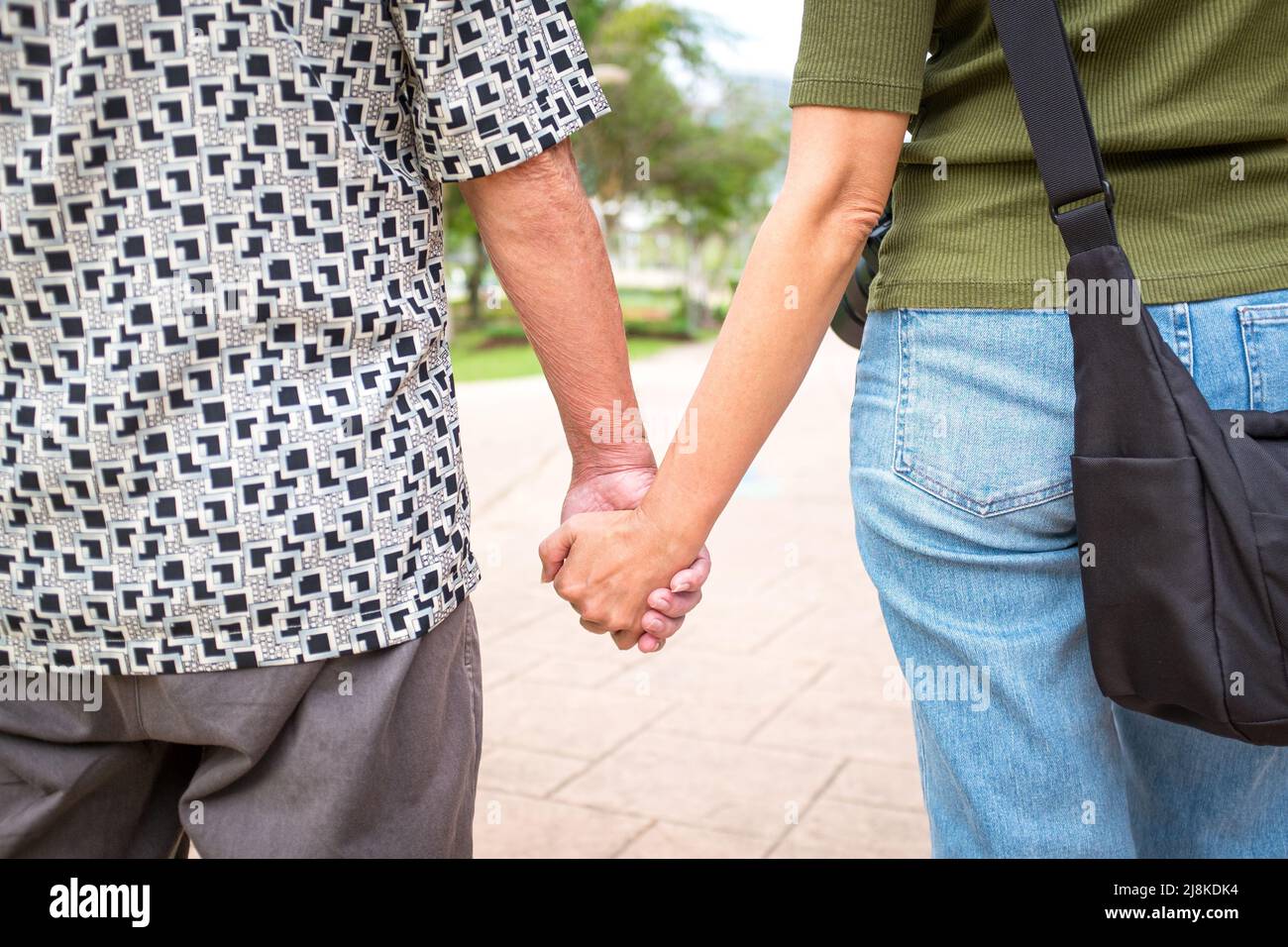 Senior man father and daughter holding hands while walking in the park ...