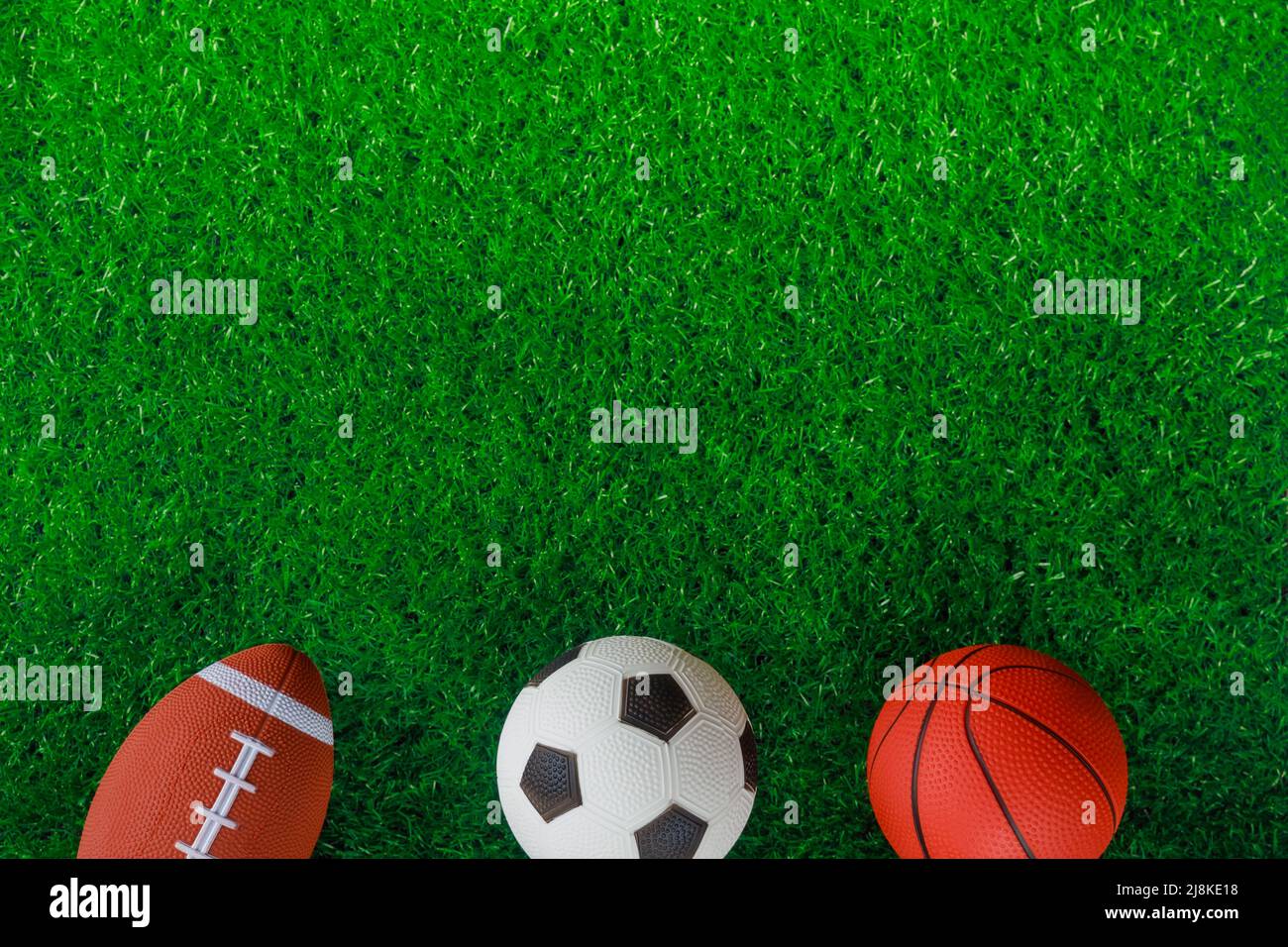 Top view of soccer, basketball and football balls on green background
