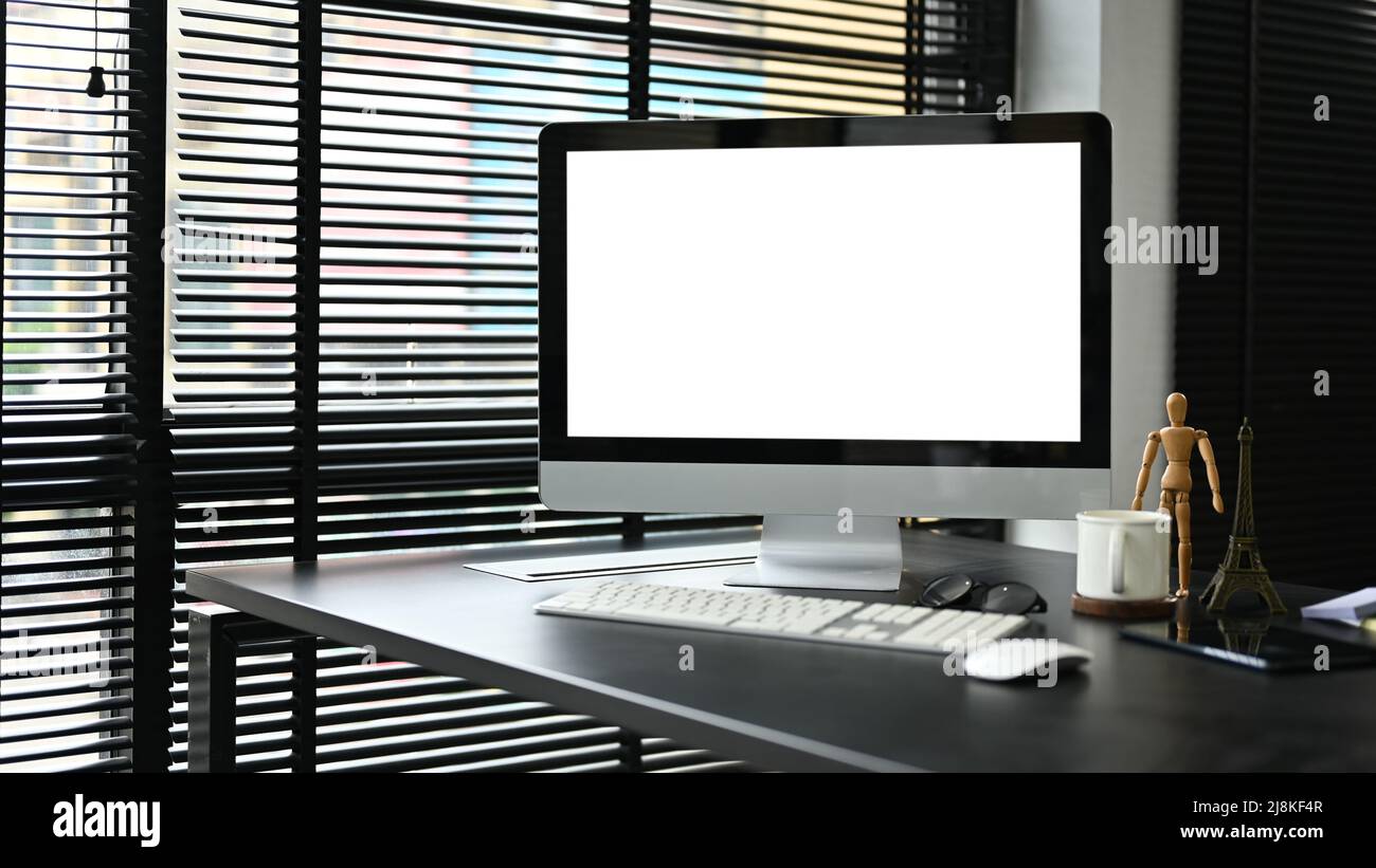 A PC computer white screen mockup on a modern dark office desk in the