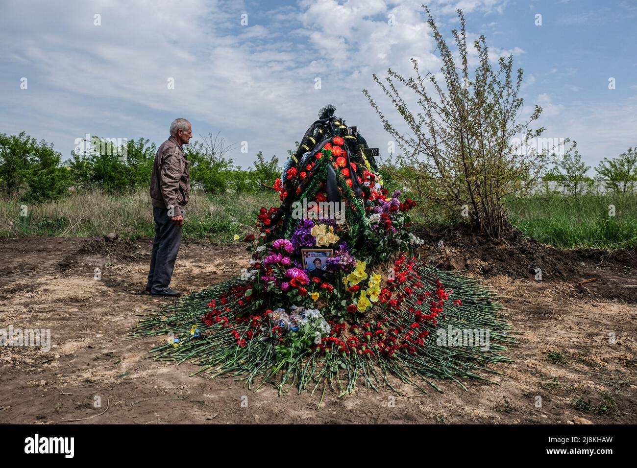 Balabyne, Ukraine. 13th May, 2022. A father stands in front of the grave of his son, Sergey Titov, 32 years old, sergeant of the National Guard, killed by a Russsian shelling in Balabyne village. Russia invaded Ukraine on 24 February 2022, triggering the largest military attack in Europe since World War II. (Credit Image: © Rick Mave/SOPA Images via ZUMA Press Wire) Stock Photo