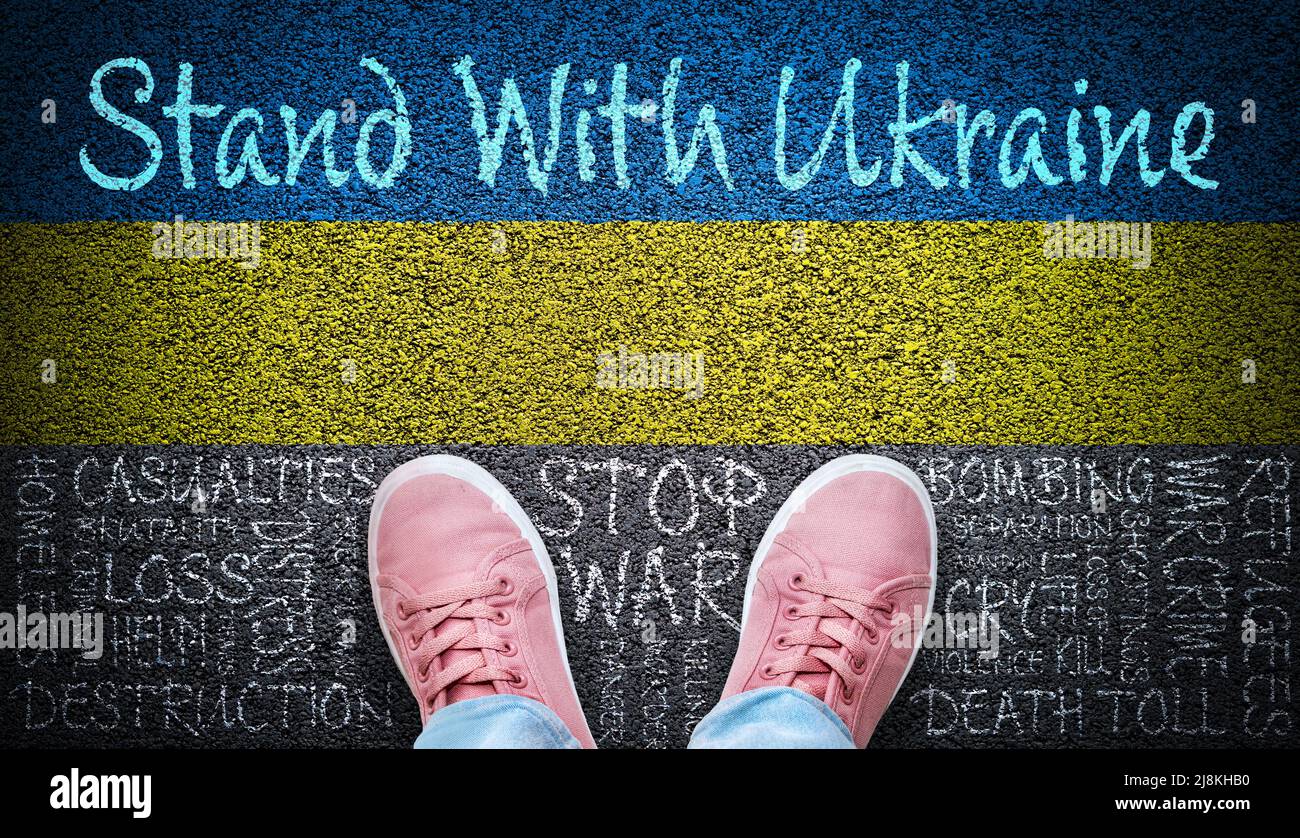 Person standing with Ukraine message on asphalt with painted Ukraine flag and Stop the War word cloud and consequences of war written on the road. Stock Photo