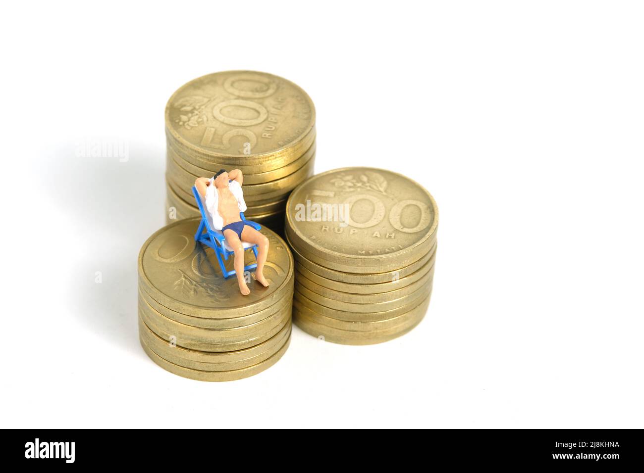 Miniature people toy figure photography. Budget and Financial Plan for travel. Men relaxing seat at beach chair above money coin stack, isolated on wh Stock Photo