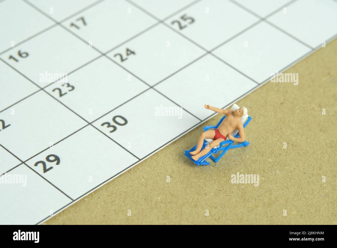 Miniature people toy figure photography. Travel plan schedule concept, men relaxing at beach chair with calendar. Image photo Stock Photo