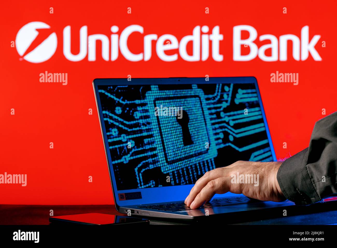 Laptop with lock symbol on screen on background of  UniCredit bank logo. Finger points to lock symbol. Concept of data hacking. Stock Photo
