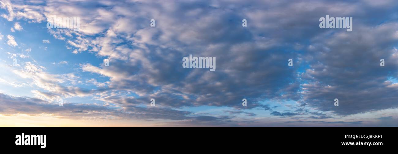 panorama of a sky with glowing clouds at sunrise. wide cloudscape above the mountain ridge. summer nature background on a sunny weather morning Stock Photo