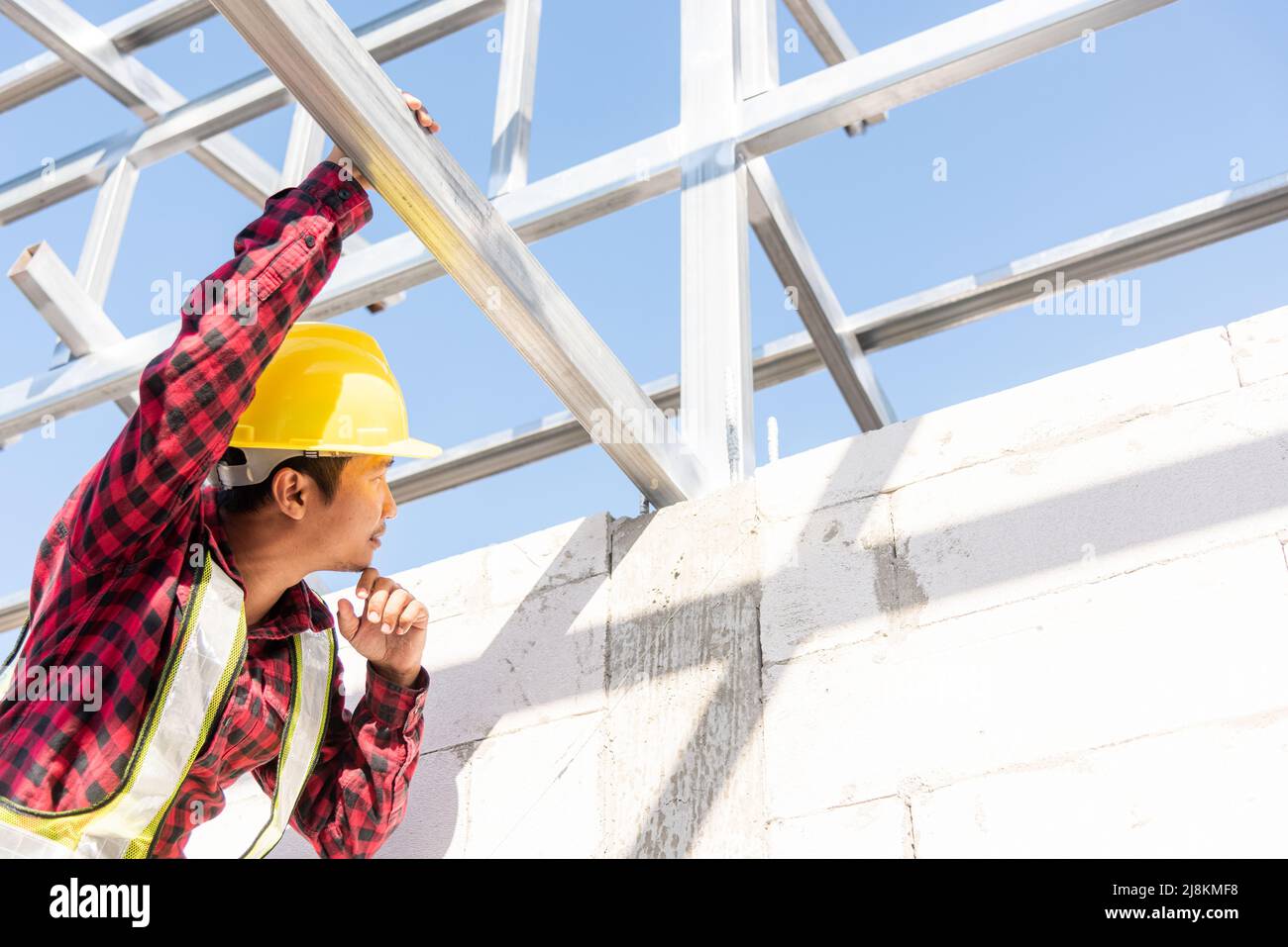 Construction worker or contractor checking house frame, worker roofer builder working on steel roof structure on building construction site Stock Photo